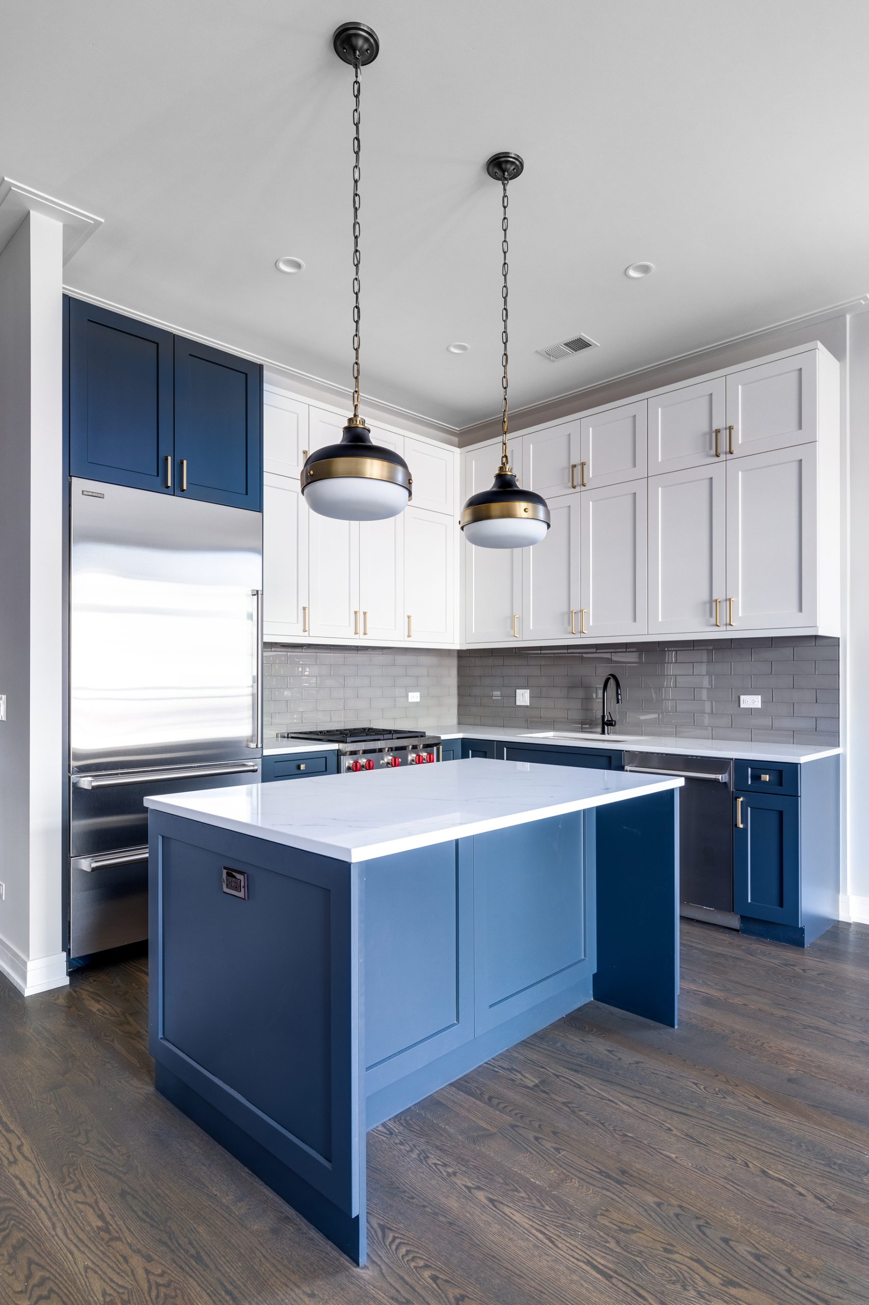 CHICAGO, IL, USA - JANUARY 6, 2020: Blue and white cabinets in a modern kitchen with a blue island, white granite counter top and lights off. Subway tiles make for a beautiful back splash.